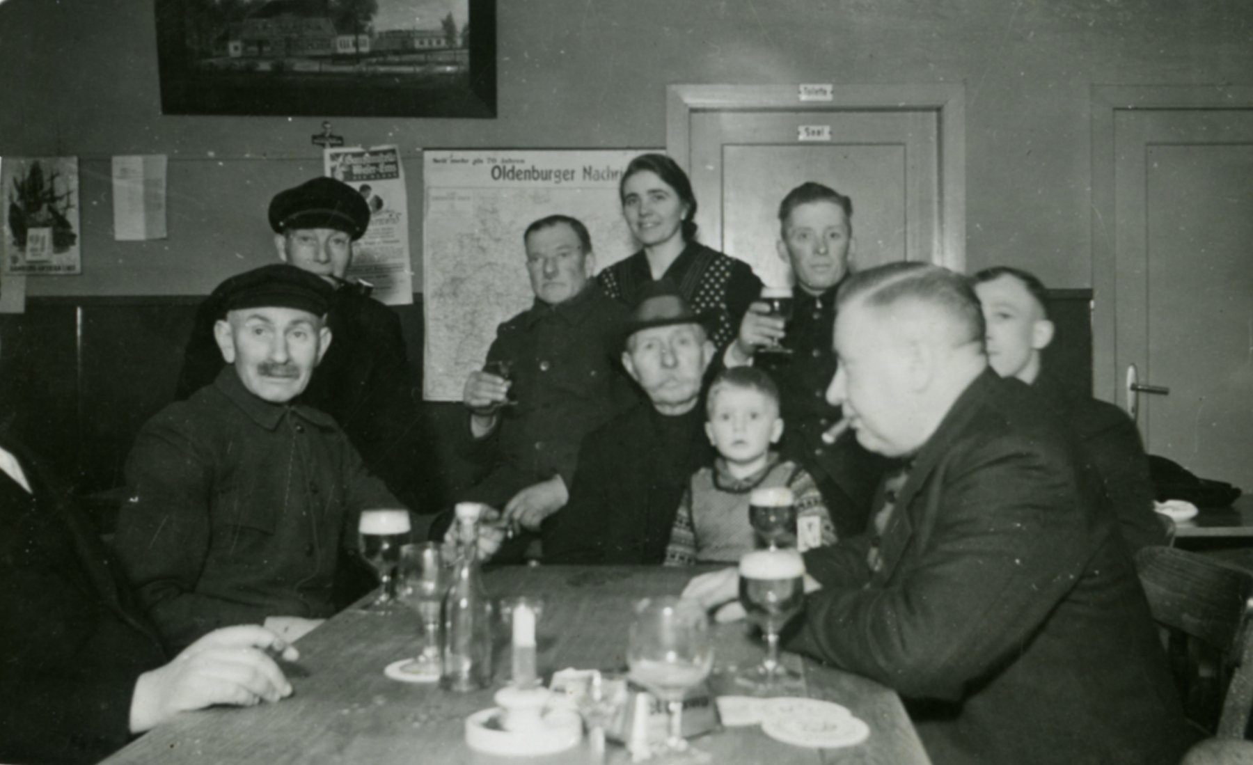 Wirtin Luise Willers mit Gästen, Kriegswinter 1940, v. l.: Hermann Brockmann, Hermann Schrader, Friedrich Bohlen, Luise Willers, Opa Heinrich Stöver, auf dem Schoß Heinz Willers, Willi Willers, Gerhard Martens und Karl Mehl.